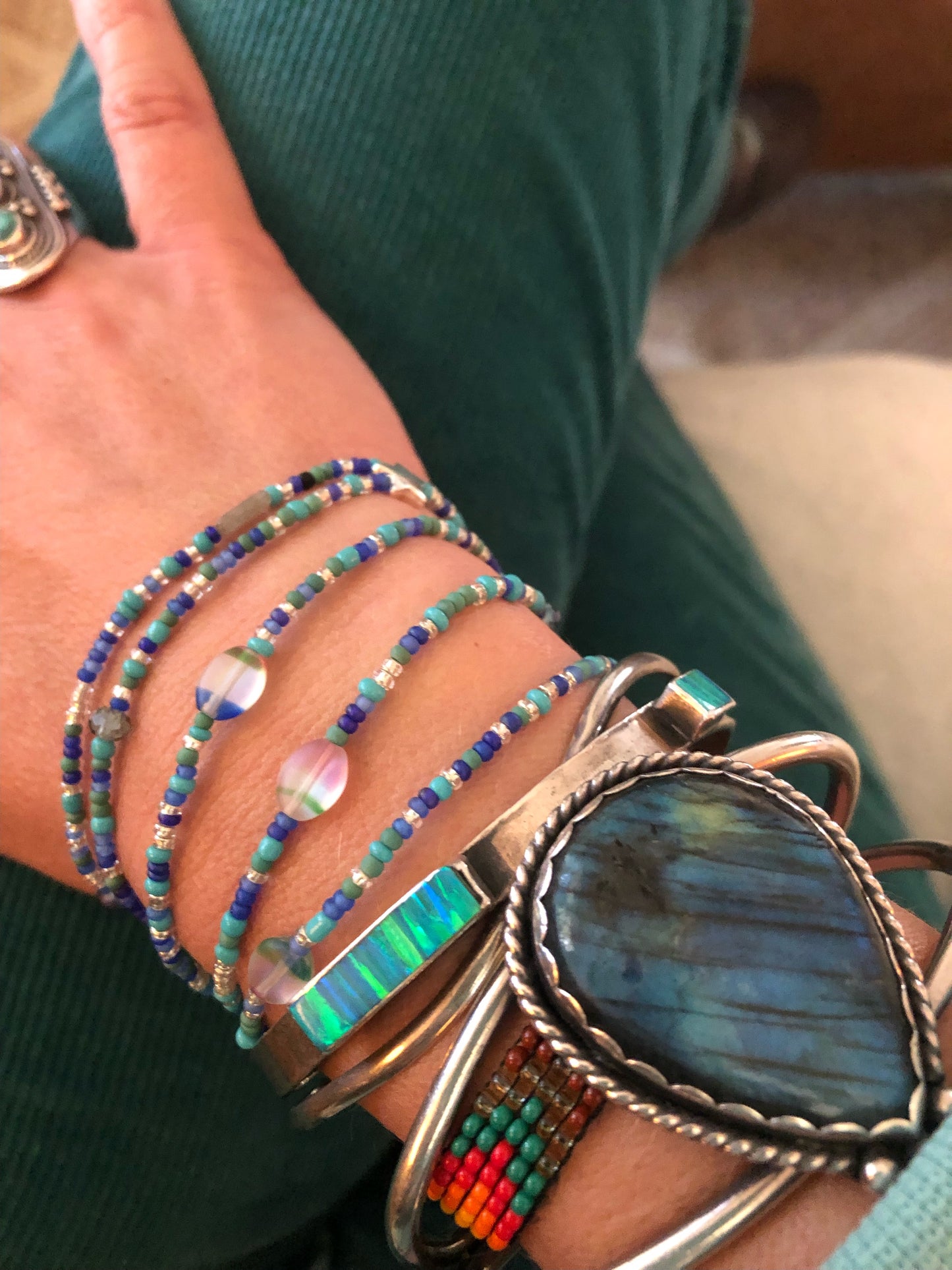 Waist beads in blue, green, and silver glass seed beads, silver plated star beads, multi-colored glass beads, and labradorite beads on elastic cord with a silver plated clasp.