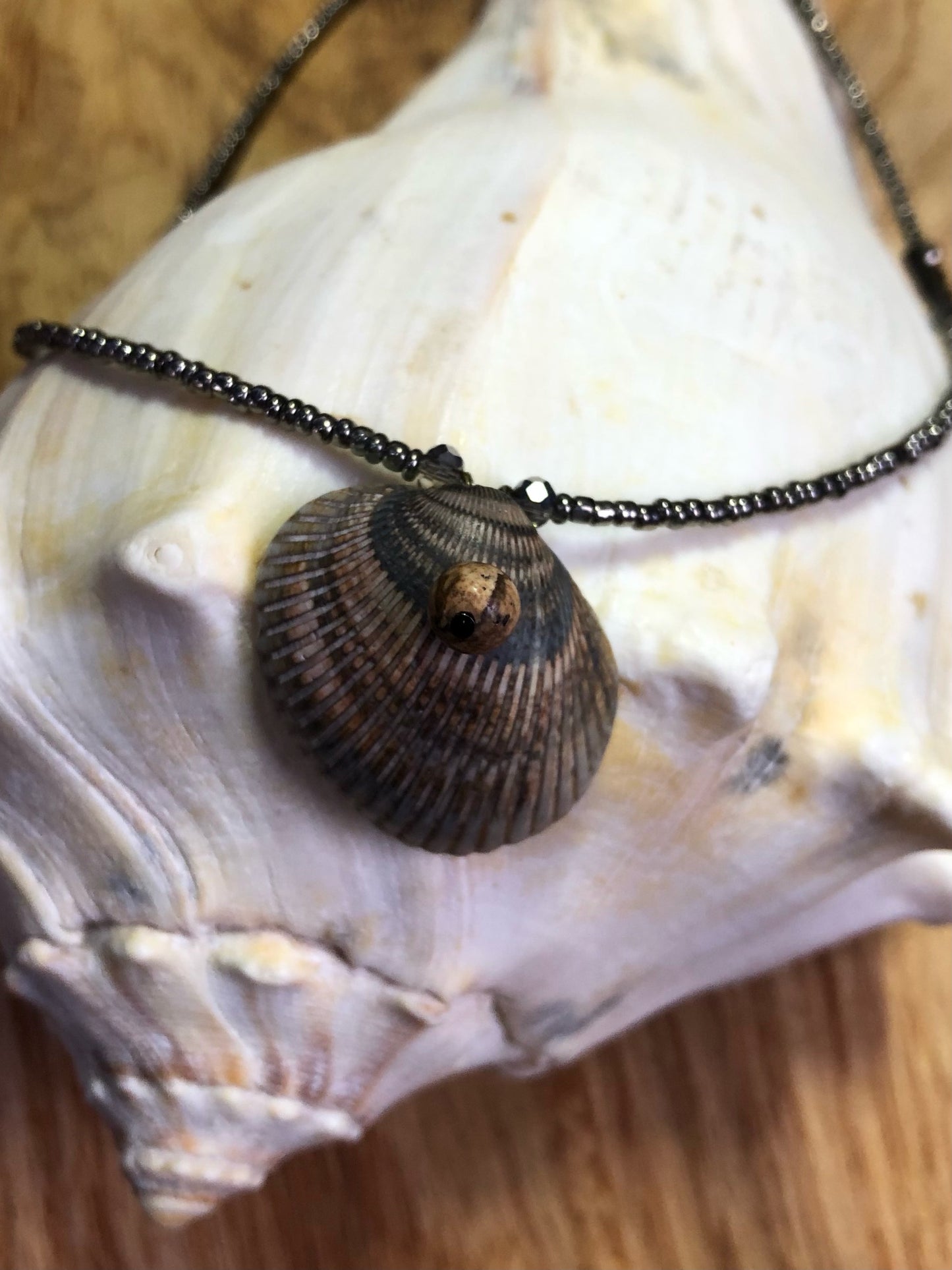 Seashell necklace with gunmetal glass seed beads, hematite v-shaped beads, and black Austrian glass crystal beads.