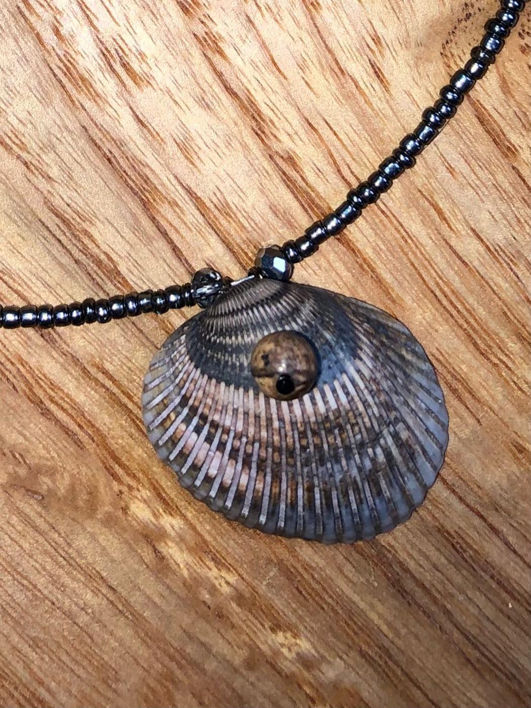 Seashell necklace with gunmetal glass seed beads, hematite v-shaped beads, and black Austrian glass crystal beads.
