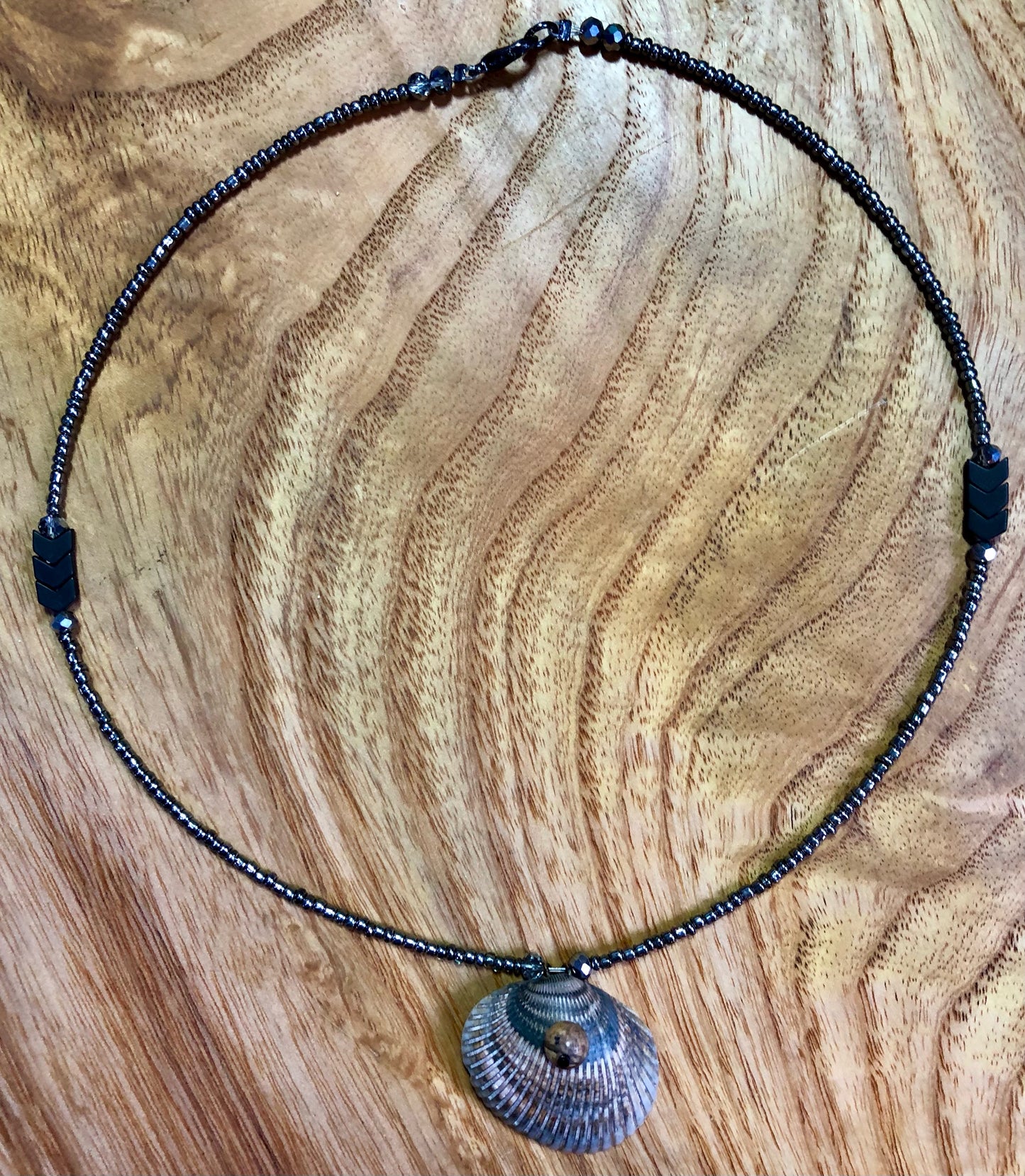 Seashell necklace with gunmetal glass seed beads, hematite v-shaped beads, and black Austrian glass crystal beads.