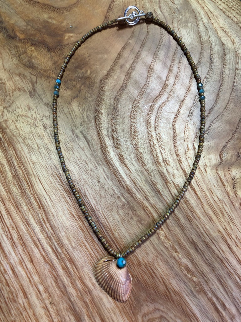 Sandy colored seashell necklace with sand colored glass seed beads and blue glass beads.