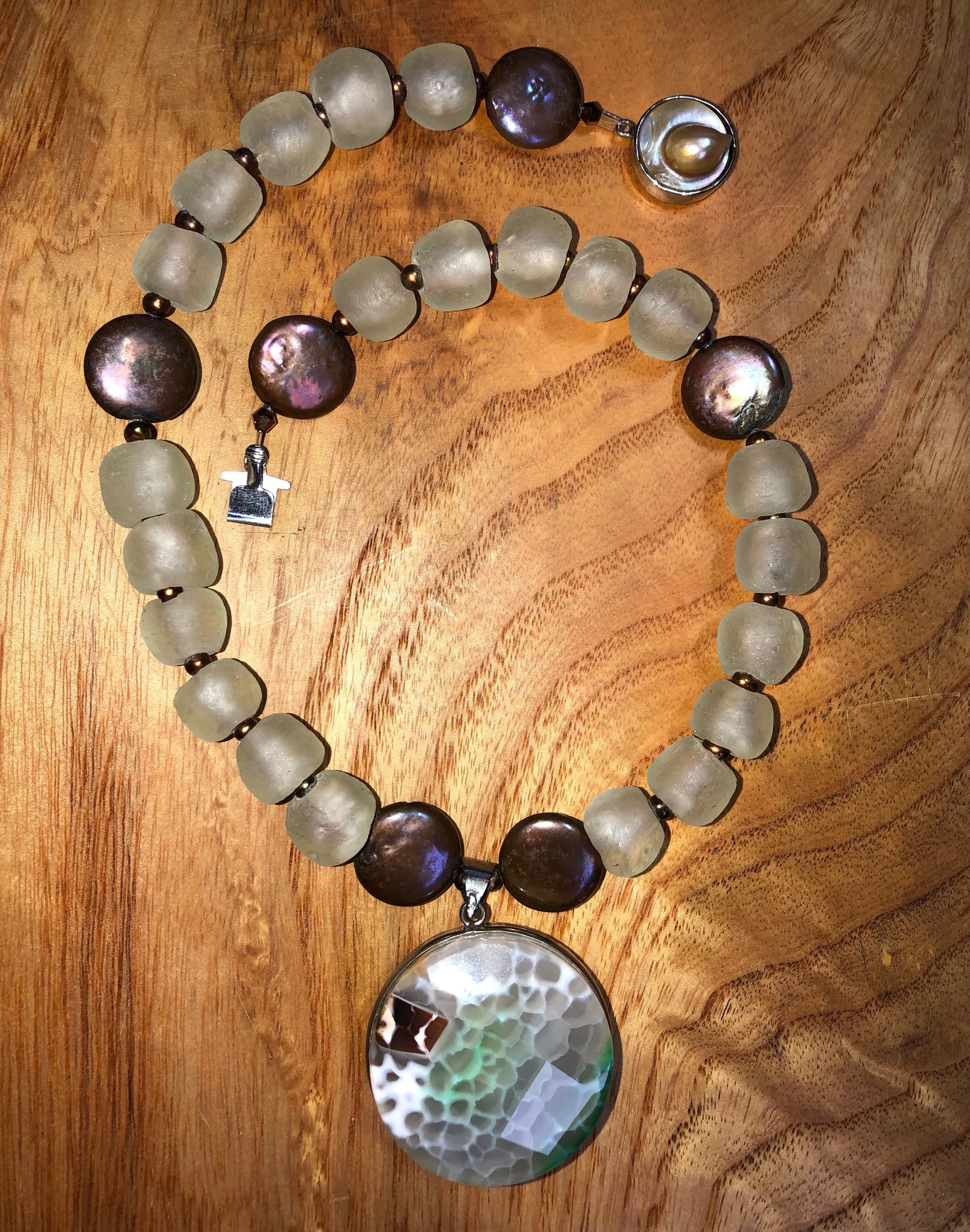 Faceted multi-color agate pendant set in sterling silver with copper coin freshwater pearls, copper freshwater pearls, clear recycled glass beads, and a silver plated pearl clasp.